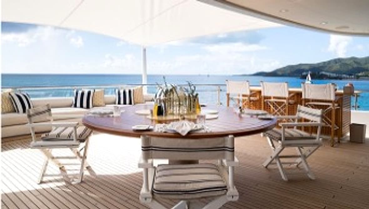 Open-air yacht dining deck with table set toward the sea